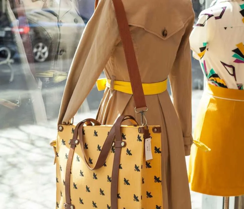 A shop window display, with a mannequin with a dress and a bag