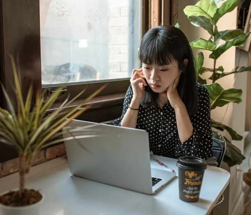 Girl sitting in a cafe at a laptop applying for jobs